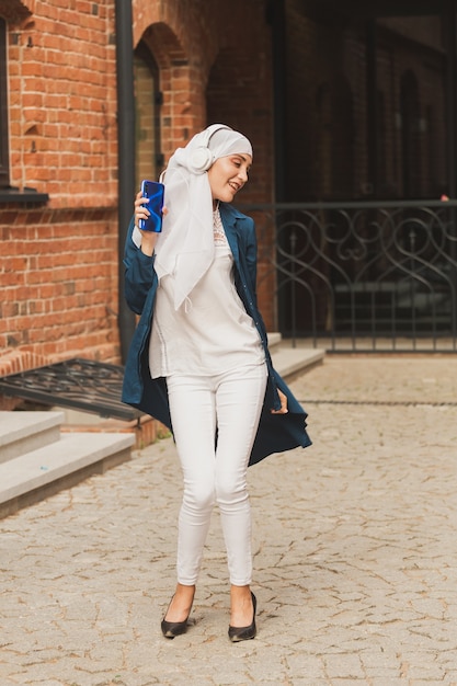 Portrait of young arabian muslim woman listening music with headphone and dancing feminism woman