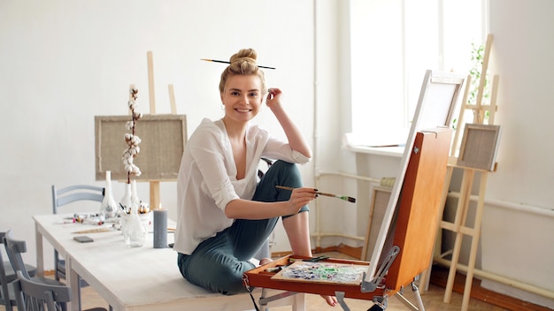 Portrait of a young artist on the side, a girl draws on canvas in the Studio