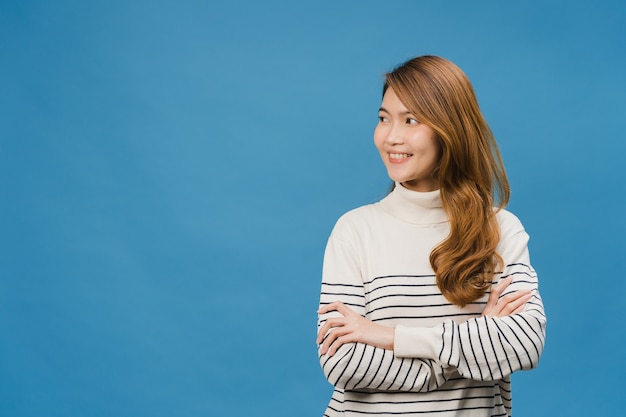 Portrait of young Asia lady with positive expression, arms crossed, smile broadly, dressed in casual clothing and looking at space over blue wall