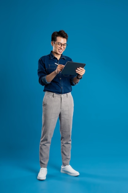 Portrait of young Asian business man posing on blue background