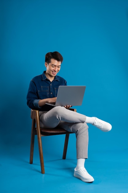 Portrait of young Asian business man posing on blue background