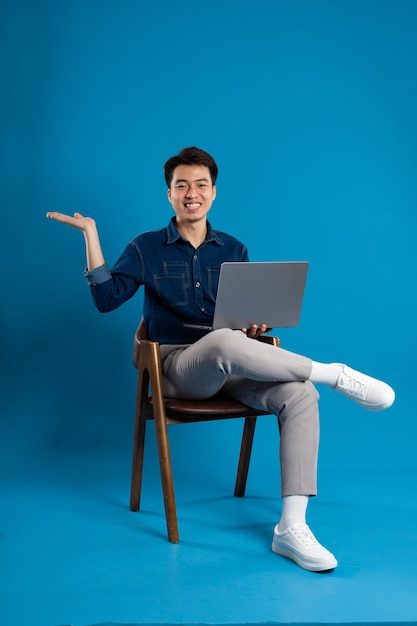 Portrait of young Asian business man posing on blue background