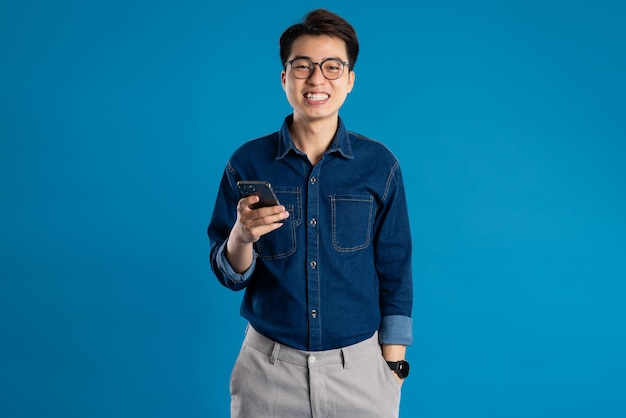 Portrait of young Asian business man posing on blue background