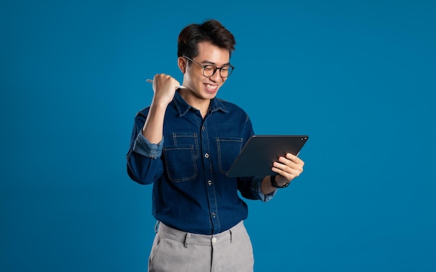 Portrait of young Asian business man posing on blue background