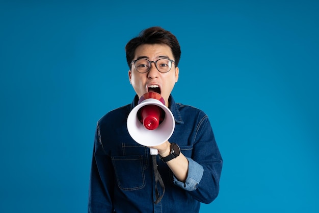 Portrait of young Asian business man posing on blue background