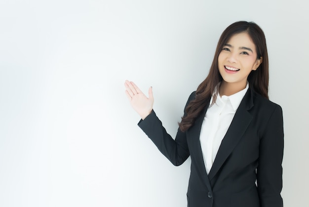 Portrait of young asian business woman pointing up over white background.