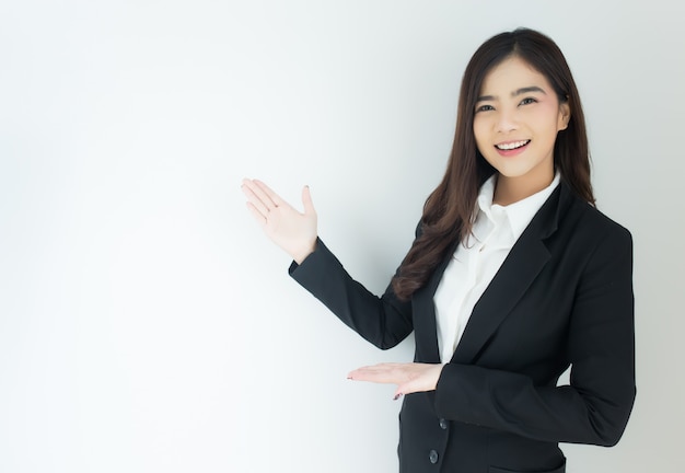 Portrait of young asian business woman pointing up over white background.