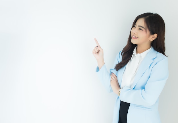 Portrait of young asian business woman pointing up over white background.