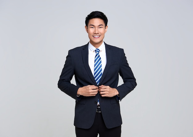 Portrait of young Asian businessman smiling confidently while standing on studio white.