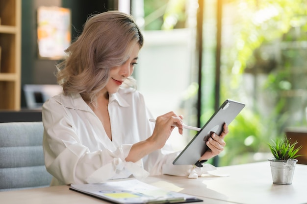 Portrait young asian businesswoman happy sitting in office with digital tablet communication professional online working job digitalxA