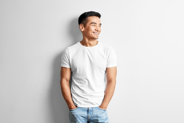 Portrait of young asian designer dressed in casual against white wall. Handsome Kazakh man joyfully smiles in studio