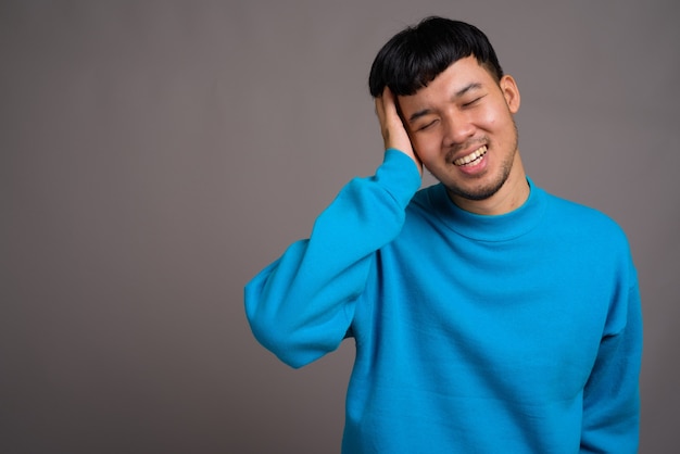 Portrait of young Asian man against gray