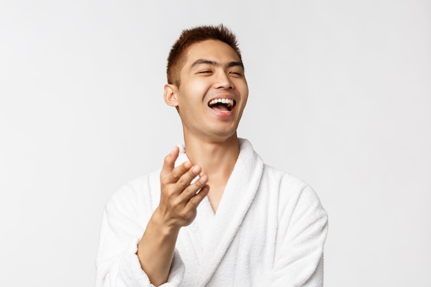 Portrait of young Asian man in bathrobe showing gesture. After shower