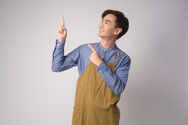 Portrait of young asian man wearing apron over white background studio