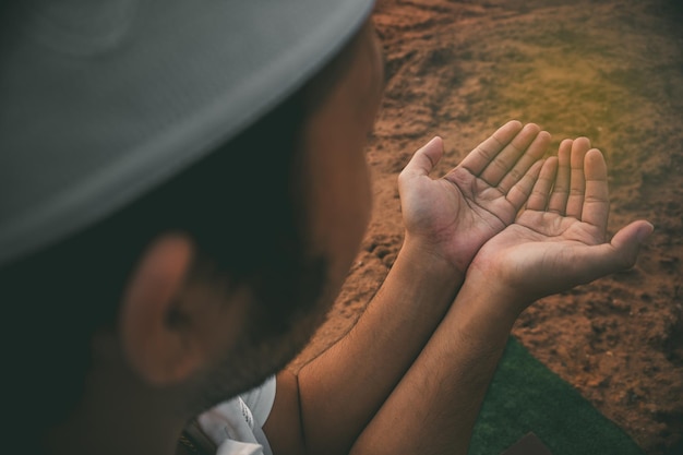 Portrait of Young asian muslim man praying on sunsetRamadan festival conceptReading a book