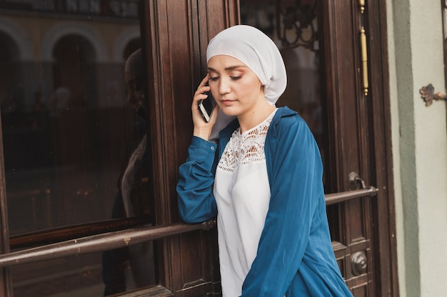 Portrait of young asian muslim student woman talking on the mobile phone outdoors