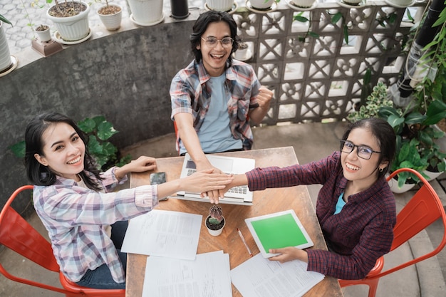 Portrait of young asian students meeting in a cafe doing high five together