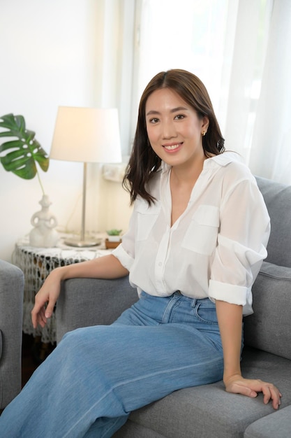 Portrait of young asian woman smiling on sofa in living room