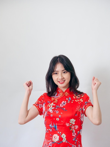 Portrait of young asian woman wearing traditional cheongsam qipao dress over isolated white background holding copyspace with two hands