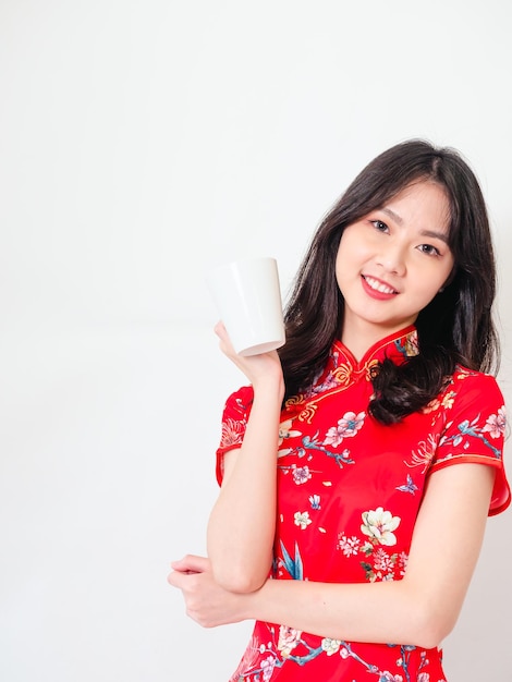 Portrait of young asian woman wearing traditional cheongsam qipao dress relaxing drinking on white background