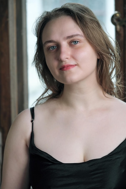 Portrait of a young attractive brownhaired girl in a black dress on a green background closeup