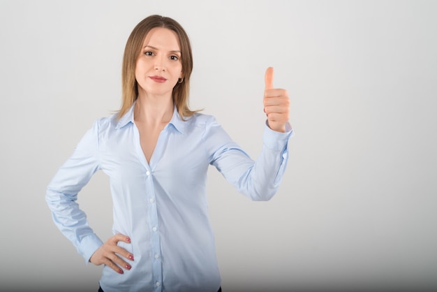 Portrait of young attractive business lady showing big thumb up sign with her fingers over white background