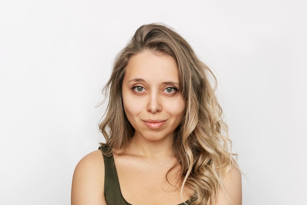 Portrait of a young attractive caucasian smiling blonde woman with wavy hair on a white background