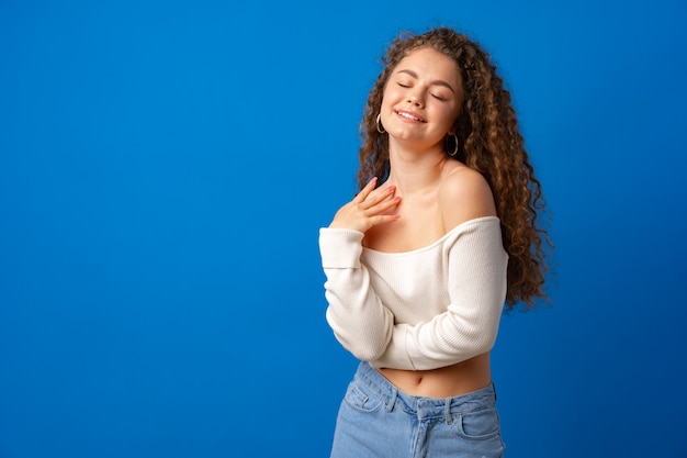 Portrait of a young attractive curlyhaired woman against blue background