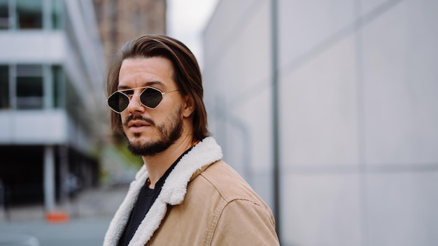 Portrait of young attractive man in casual clothes wearing sunglasses and posing on the street in