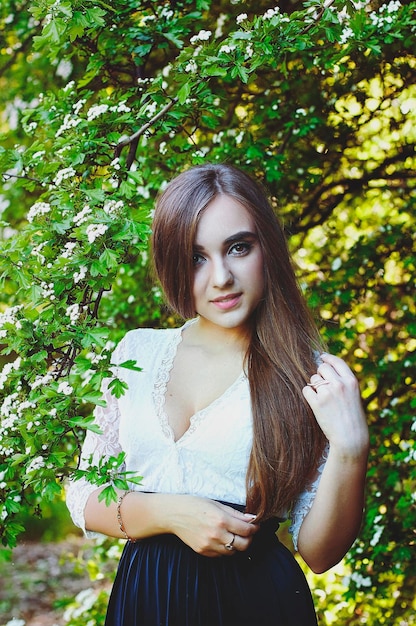 Portrait of young attractive woman in spring garden with pink blooming magnolias. Spring background