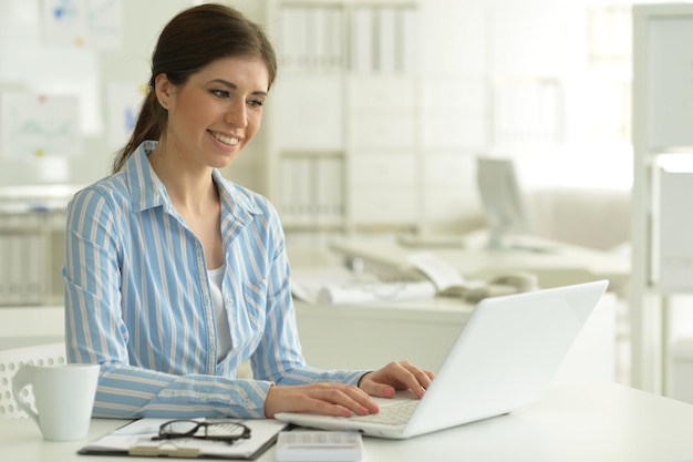 Portrait of young attractive woman working with laptop in office