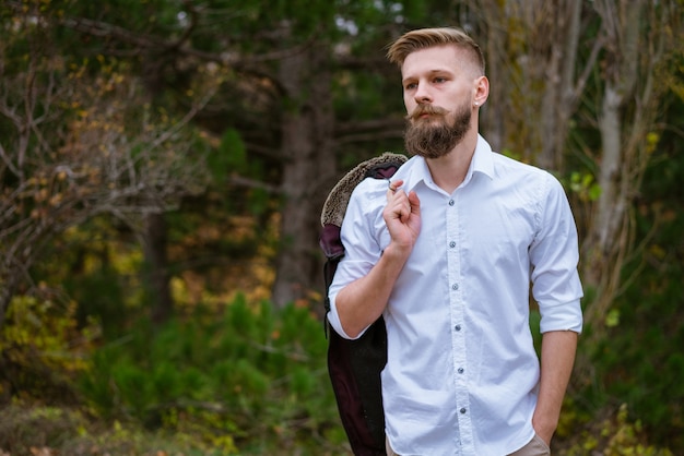 Portrait of a young bearded man walking on the road in the park in autumn handsome caucasian man in