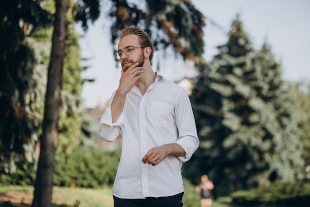 Portrait of young bearded man wearing spectacles and walking in park