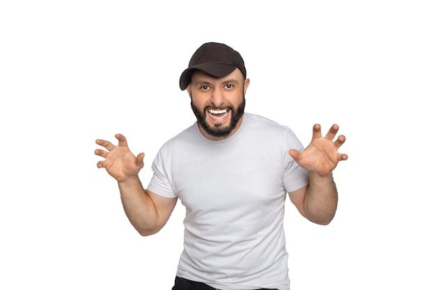 Portrait of young bearded man with white tshirt and the cap looking at camera The man posing with his hands like claws Studio shot isolated on white background