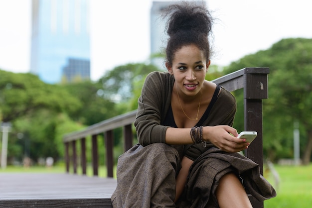 Portrait of young beautiful African woman with Afro hair relaxing at the park outdoors