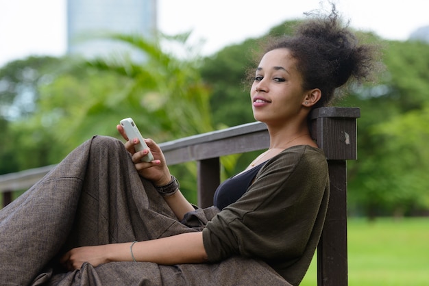 Portrait of young beautiful African woman with Afro hair relaxing at the park outdoors