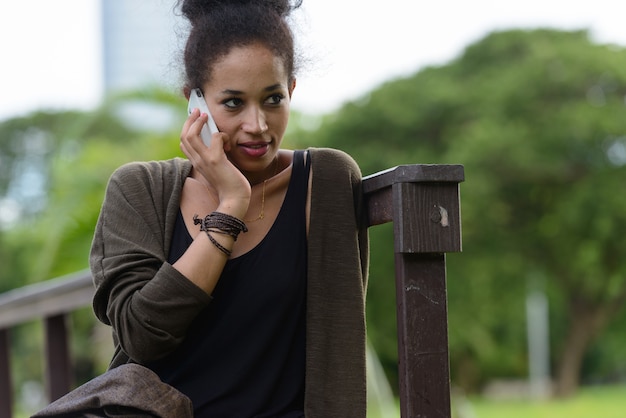 Portrait of young beautiful African woman with Afro hair relaxing at the park outdoors