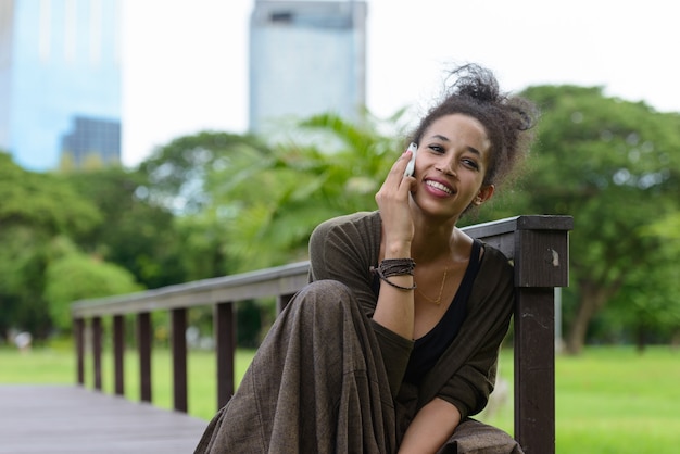 Portrait of young beautiful African woman with Afro hair relaxing at the park outdoors