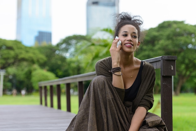 Portrait of young beautiful African woman with Afro hair relaxing at the park outdoors