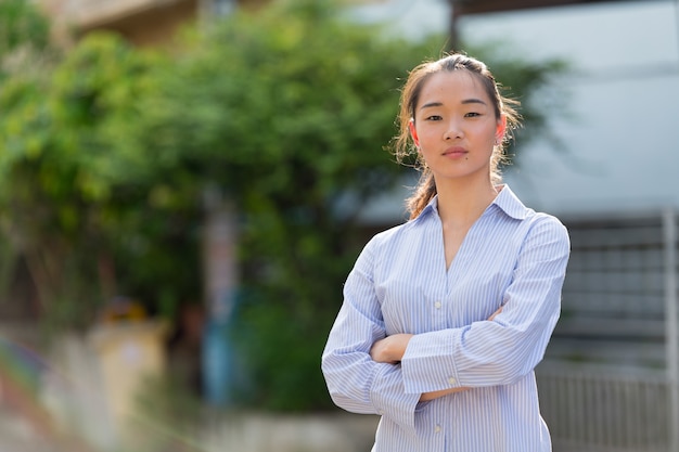 Portrait of young beautiful Asian businesswoman in the streets outdoors