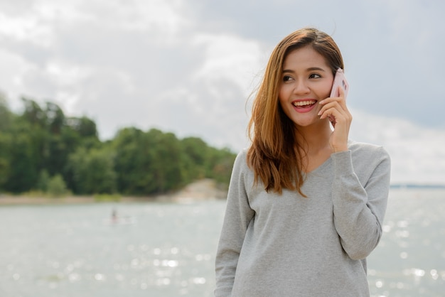 Portrait of young beautiful Asian woman against scenic view of the lake and sky in nature