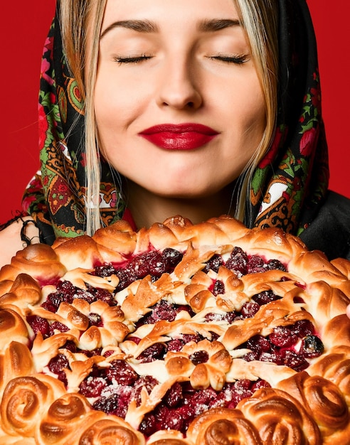 Portrait of a young beautiful blonde in headscarf holding a delicious homemade berry pie