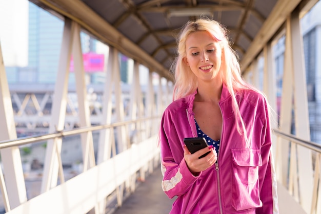 Portrait of young beautiful blonde woman at footbridge in the city outdoors