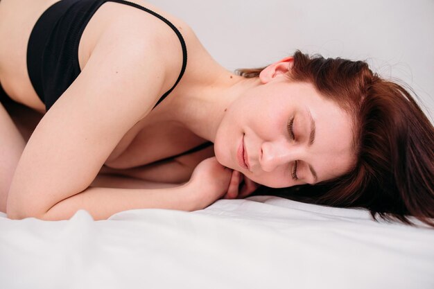 Portrait of a young beautiful brunette lying in bed wearing underwear