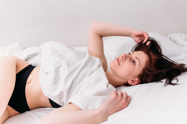 Portrait of a young beautiful brunette lying in bed wearing underwear