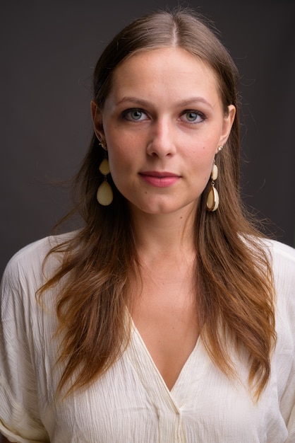 Portrait of young beautiful businesswoman against gray wall