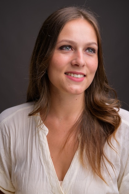 Portrait of young beautiful businesswoman against gray wall