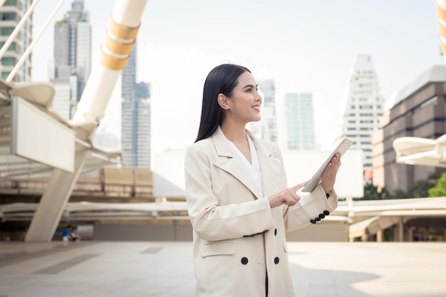 Portrait of young beautiful businesswoman using tablet in modern city