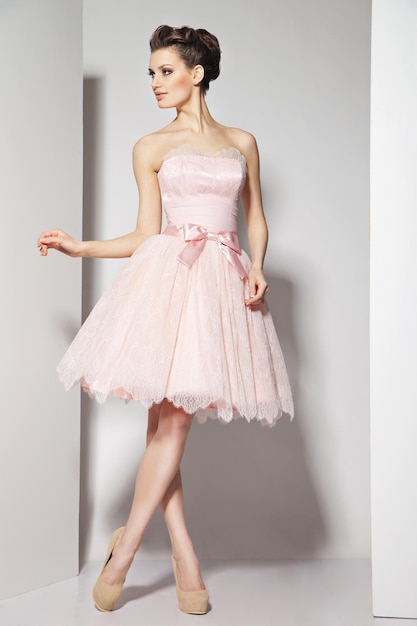 Portrait of young beautiful caucasian brunette in gorgeous dress on white background