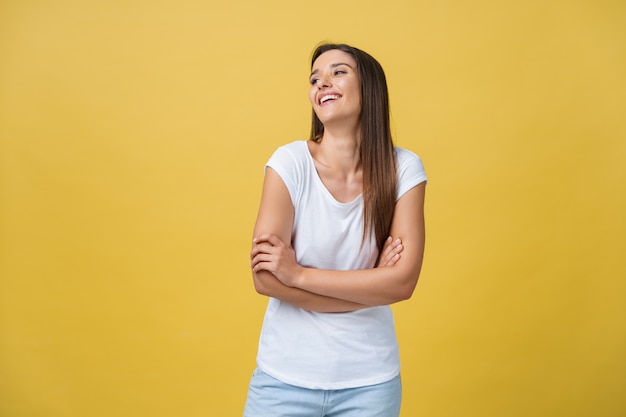 Portrait young beautiful caucasian girl with an white shirt laughing over yellow background.